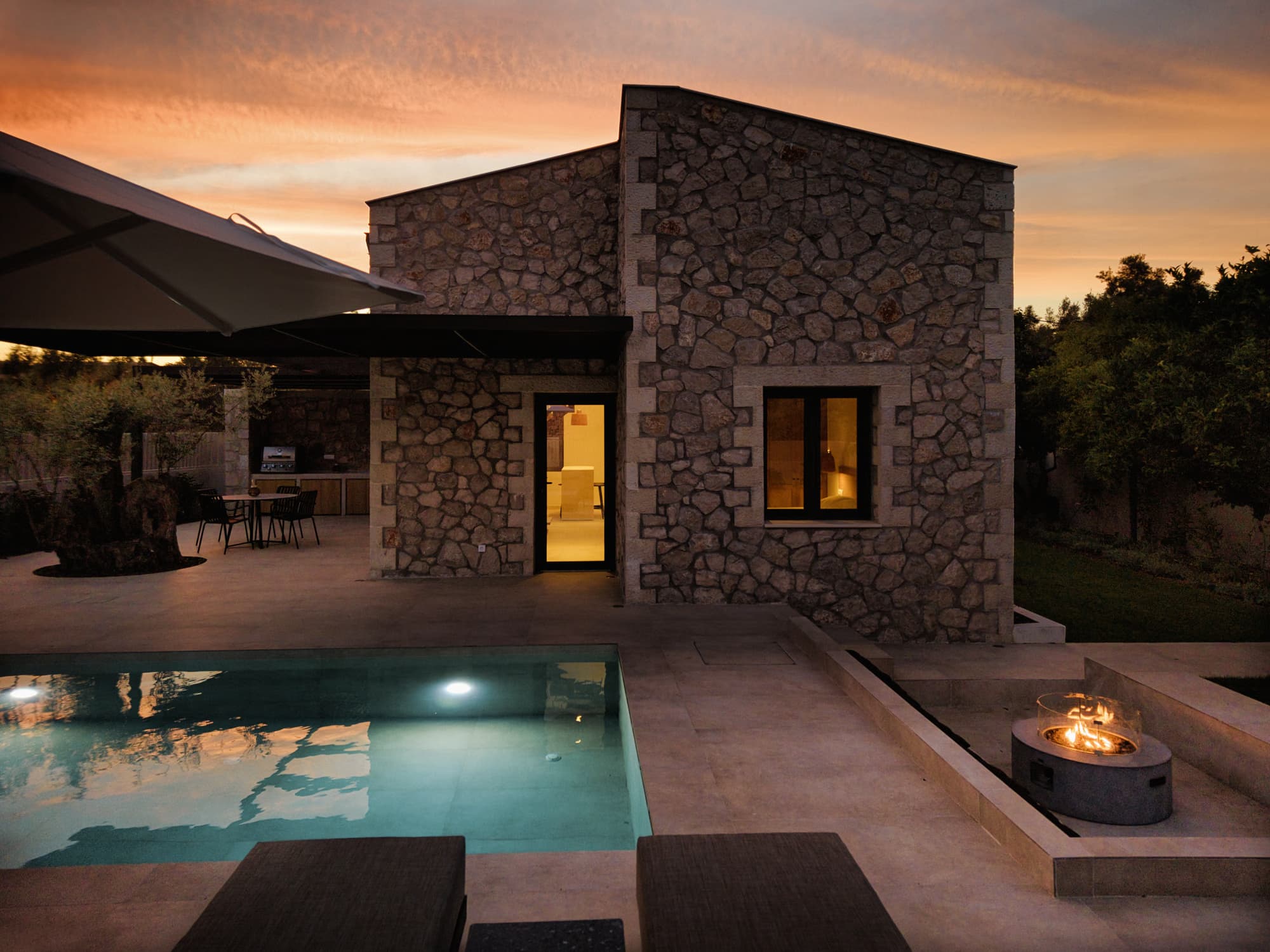 Revello Villa 1 stone facade, private pool, and fire bowl at sunset