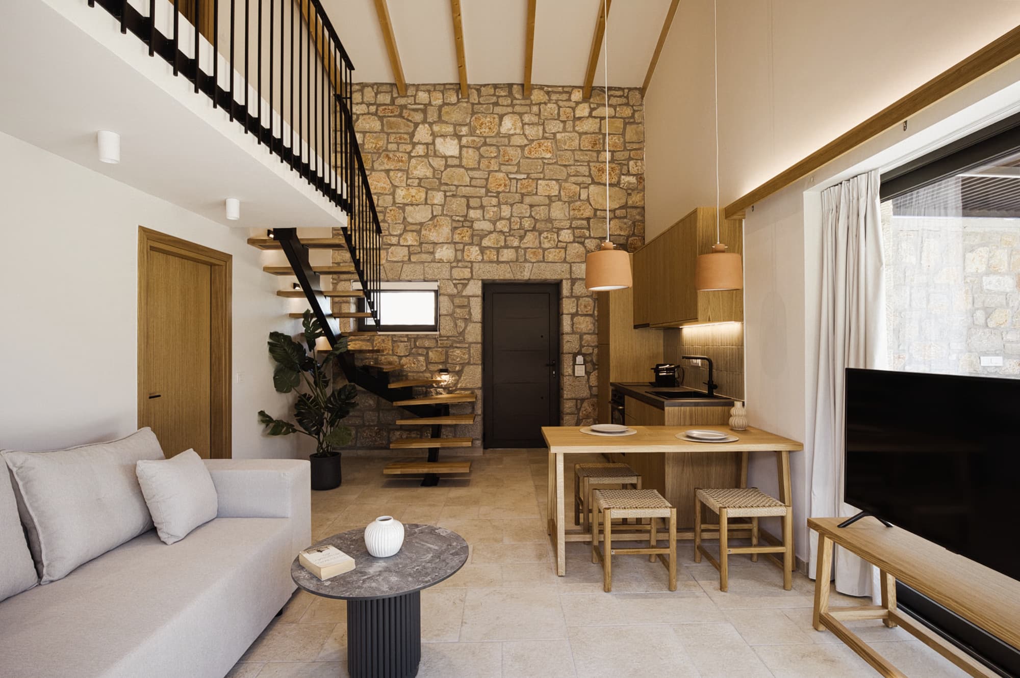 Revello Villa 2 living room with exposed stone wall and loft stair