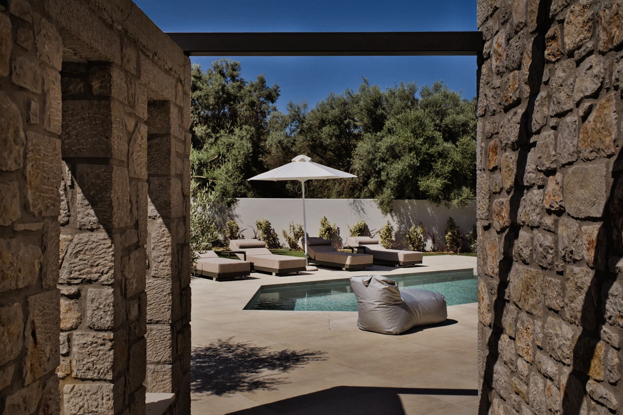 Revello Villa 3 pool and loungers framed by the stone pergola
