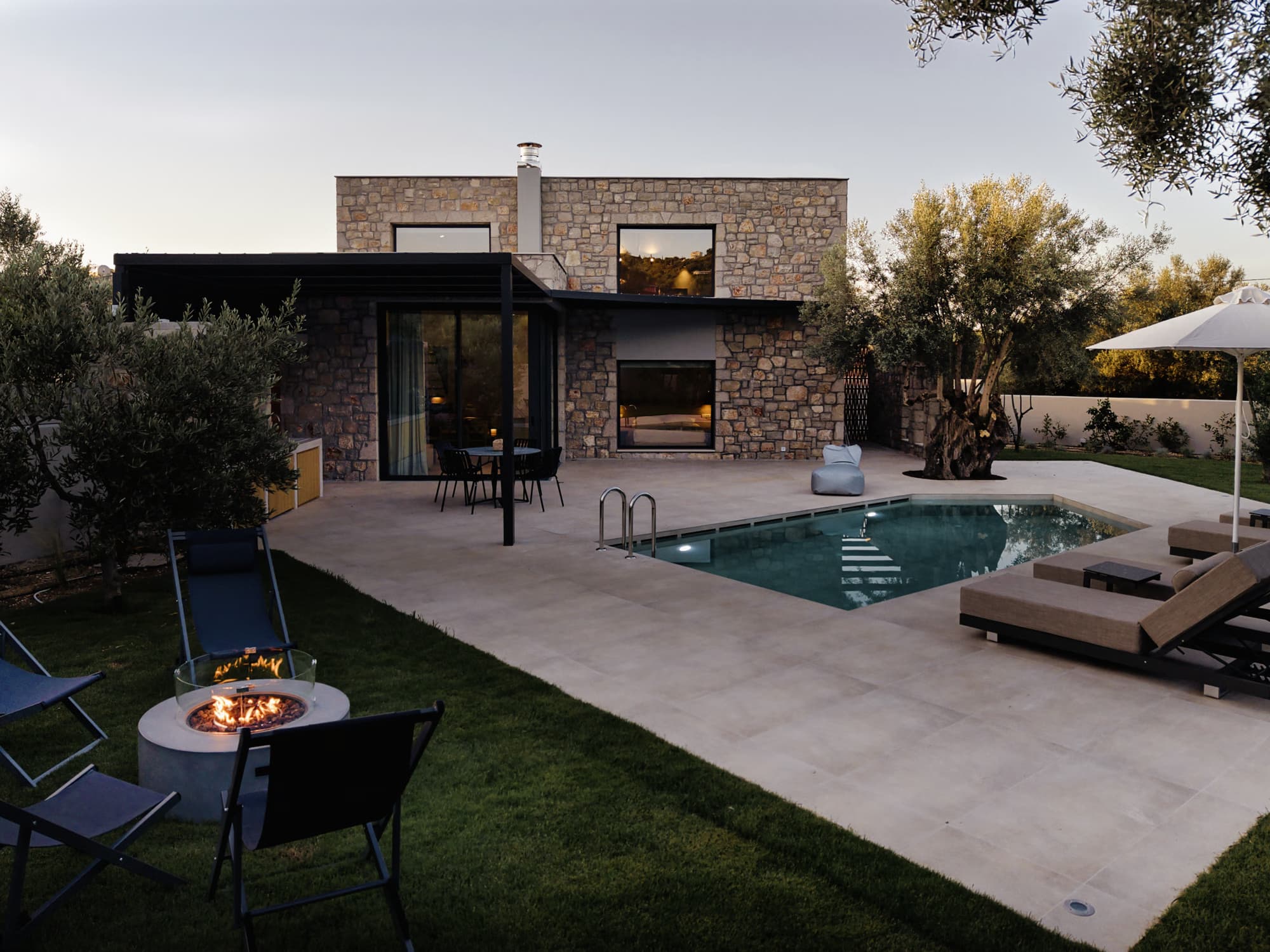 Revello Villa 4 lawn, pool, and fire bowl in the evening
